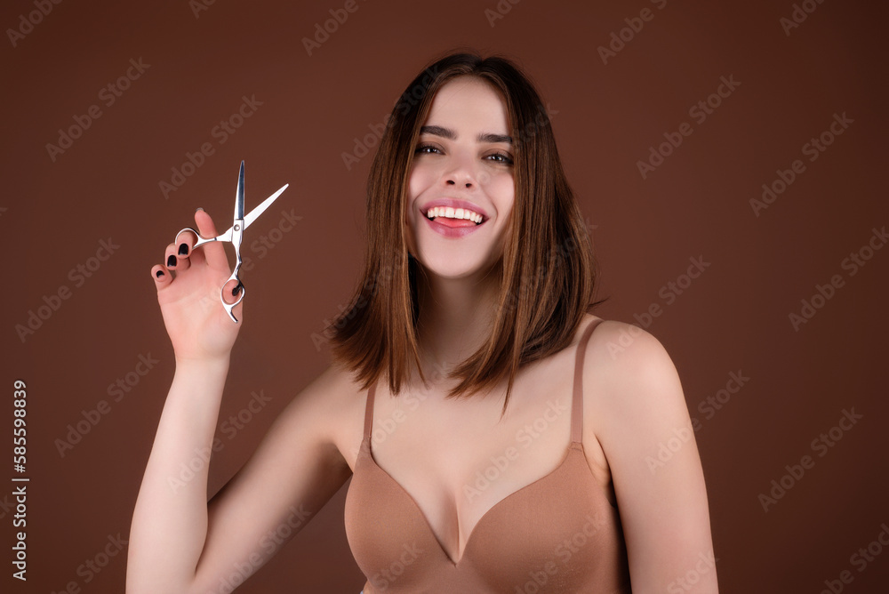 Obraz premium Beauty young woman cutting hair with scissors isolated on studio background. Beautiful girl about to cut hair. Hair cut scissors concept. Hairdresser scissors change hairstyle. Hair model hold
