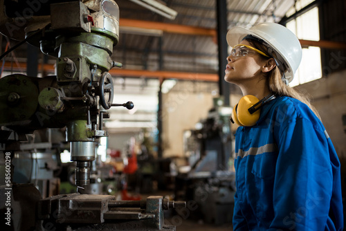 Woman worker in protective uniform operating machine at factory Industrial.
