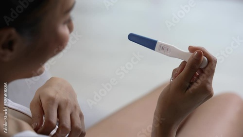 Young Asian woman feeling happy while looking at the positive results of a pregnancy test. photo