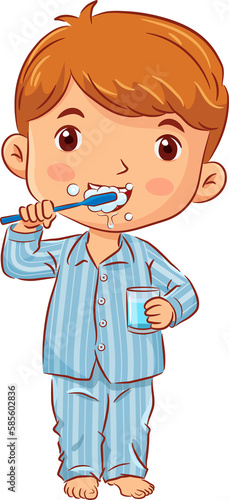 Little boy in a pyjamas stands brushing teeth and holds a glass of water in the bathroom