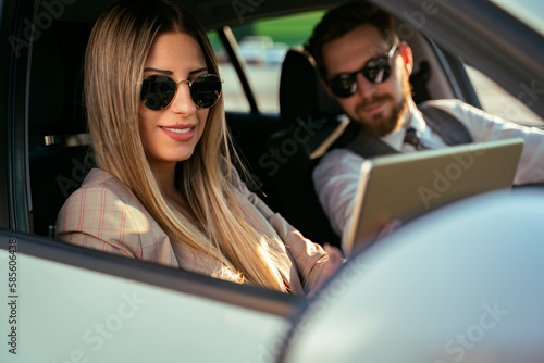 Young modern business couple sitting in a car and looking data on tablet or having video call  © phoenix021