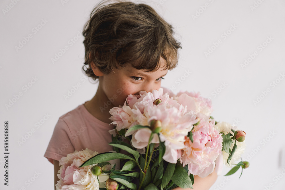 Cheerful happy child with Peonys bouquet. Smiling little boy on white background. Mother's Day. Love and romantic concept Cheerful happy child with Peonys bouquet. Smiling little boy on white background. Mother's Day. Love and romantic concept