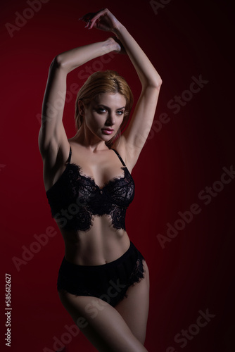 Lingerie model in sexy bra and panties. Lace black lingerie. Breast in sexy bra, natural boobs. Sensual model in sexy lingerie isolated on red studio bachground. Sexy clothes.