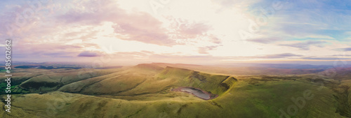 Beautiful panoramic view of the lush green landscape in Wales during sunset with rolling hills and a serene lake in the foreground photo