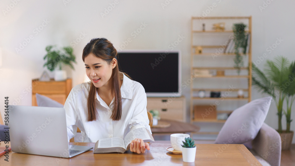 Working lifestyle at home concept, Women reading a book and working on laptop at modern home office Working lifestyle at home concept, Women reading a book and working on laptop at modern home office