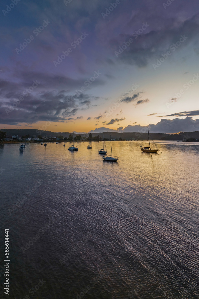Sunrise over the water with clouds and boats
