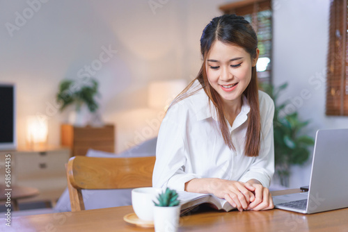 Relaxing time concept, Women read book with happiness and working on laptop at modern home office