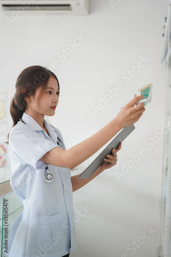 Medicine and health concept, Female pharmacist hold medicine box to checklist in paper at drugstore