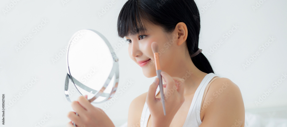 Beautiful young asian woman applying brush on cheek makeup of cosmetic looking mirror on bed, beauty of girl with skin facial and wrinkle in the bedroom, cosmetology for female, skincare concept. Beautiful young asian woman applying brush on cheek makeup of cosmetic looking mirror on bed, beauty of girl with skin facial and wrinkle in the bedroom, cosmetology for female, skincare concept.