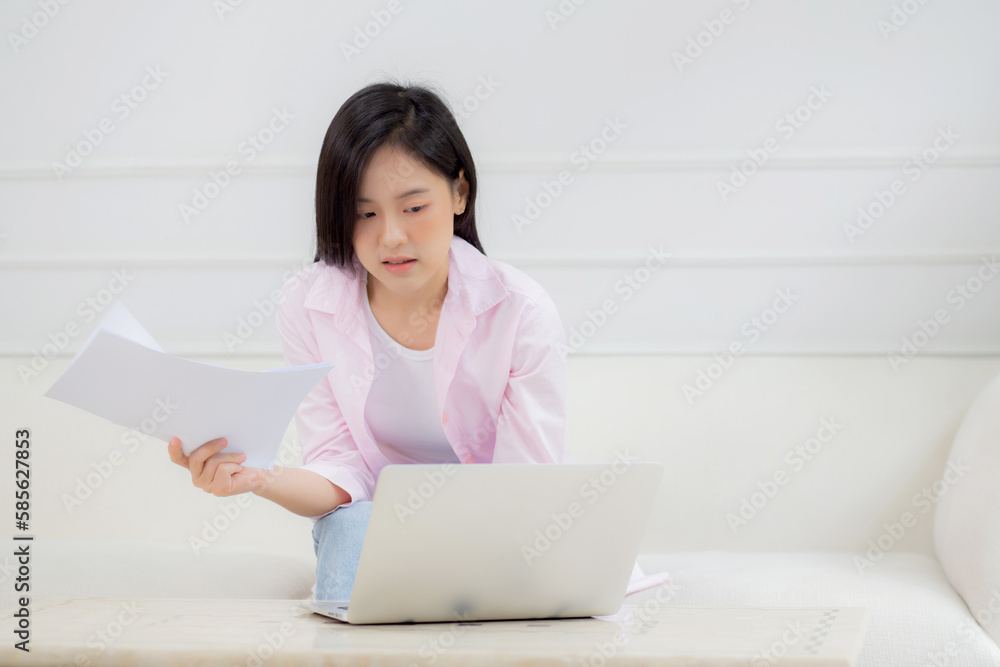 Young asian business woman working on laptop computer and looking graph and chart of report for profit on paper at home, businesswoman looking investment and income, data of infographic statistics. Young asian business woman working on laptop computer and looking graph and chart of report for profit on paper at home, businesswoman looking investment and income, data of infographic statistics.