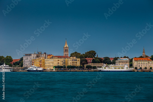 Zadar, Croatia - Panoramic view of the old town of Zadar at sunset with illuminated Cathedral of St. Anastasia bell tower, yachts and ferry and clear blue sky on a summer afternoon