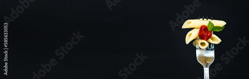 Minimal macro photography of paste with tomato sauce on fork on black background with copy space. Mockup template for keto diet or receipt book