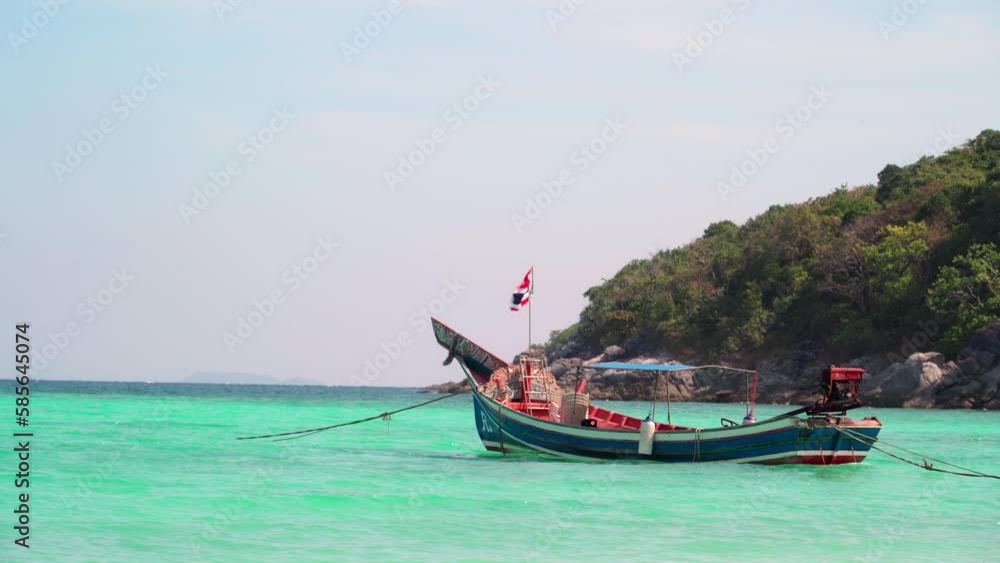 Thai traditional longtail tourist boat bobs on turquoise transparent waves near a tropical island resort near Krabi and Phuket. The concept of an exotic vacation at a seaside resort. Thai traditional longtail tourist boat bobs on turquoise transparent waves near a tropical island resort near Krabi and Phuket. The concept of an exotic vacation at a seaside resort.