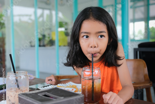 Little female girl sitting alone drinking iced lemon tea with a straw photo