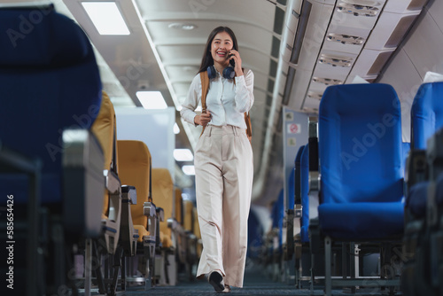 Beautiful Asian business woman talking with client by mobile phone when flight landing. working, travel, business concept