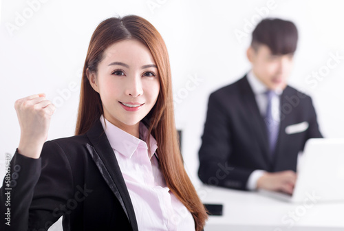 Successful business woman sitting with her staff in background at office