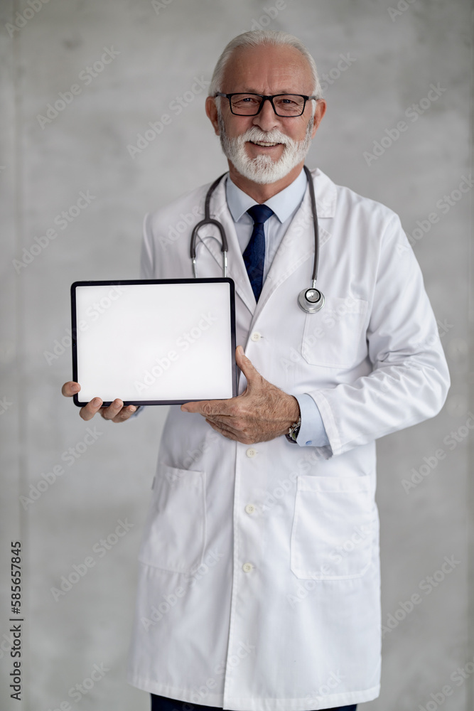 Portrait of senior male doctor holding digital tablet and showing free space Portrait of senior male doctor holding digital tablet and showing free space
