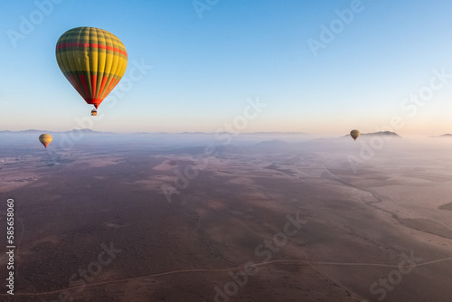 Colorful hot air balloons floating above the vast Moroccan desert expanse © Alessandro Vecchi