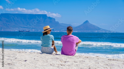 Bloubergstrand Cape Town South Africa on a bright summer day, Blouberg beach, withe powder sand and blue ocean. couple on the beach, men and woman chilling on the beach photo