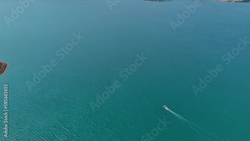 Spectacular aerial view on a big reservoir surrounded by mountains. Drone shot of a lonely boat moving across a giant lake. photo