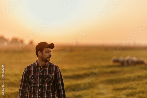 Portrait shot of a farmer watching over cattle on a farm. Man in the countryside with domestic animals during the sunset. © La Famiglia