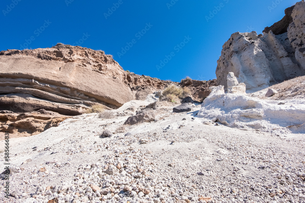 The coast of the island santorini is composed of rocky walls and sand
