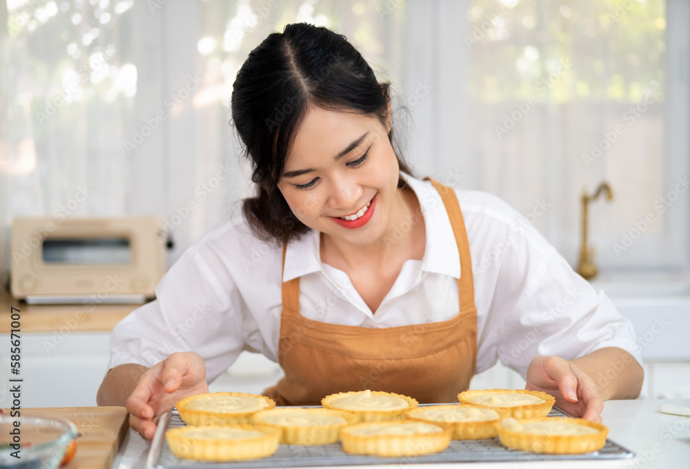 Young Happy Woman Baking Fresh fruit tart on white table in Kitchen. Smiling attractive young adult woman lady housewife baker wear apron making fruit tart on kitchen table. homemade bakery at home. Young Happy Woman Baking Fresh fruit tart on white table in Kitchen. Smiling attractive young adult woman lady housewife baker wear apron making fruit tart on kitchen table. homemade bakery at home.