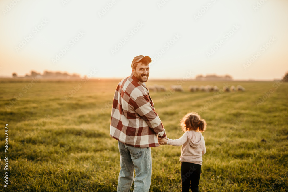 Happy family on holiday vacation. Smiling father and little daughter holding hands and walking together on the meadow field. Parent with child girl relax and enjoy an outdoor lifestyle. Copy space