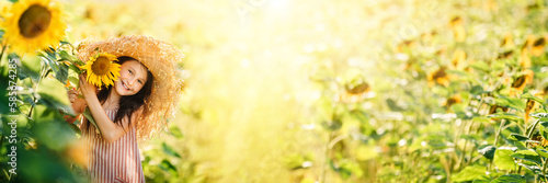 Little happy little girl playing enjoying sunflower flowers on sunny summer day field. Spring and summer background banner. Horizontal photo banner for website header design.