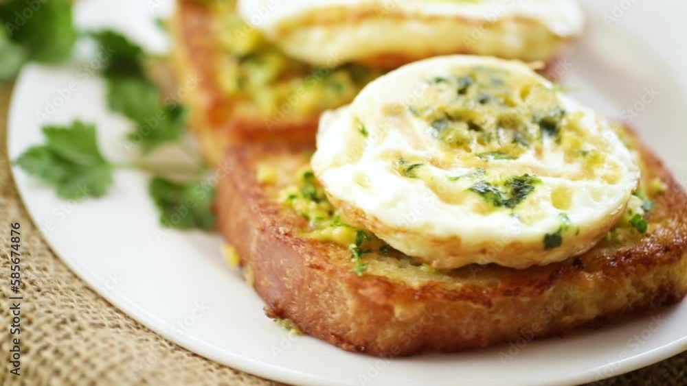 Fried croutons in batter with garlic and herbs and a fried egg in a plate, on a wooden table. Fried croutons in batter with garlic and herbs and a fried egg in a plate, on a wooden table.