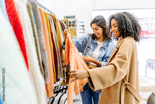 Happy young multiracial friends shopping together at clothing store
