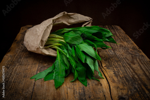 Fresh ramson in paper bag lying on wooden table photo