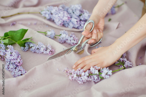Hands of woman cutting linen fabric with scissors photo
