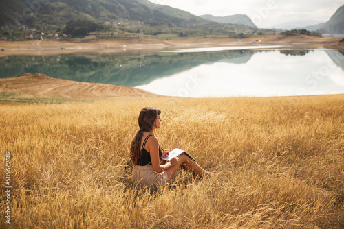 Young woman with sketch pad sitting in front of Rama Lake photo