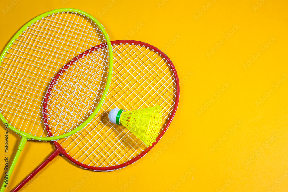 badminton rackets and shuttlecock on yellow background, sport concept