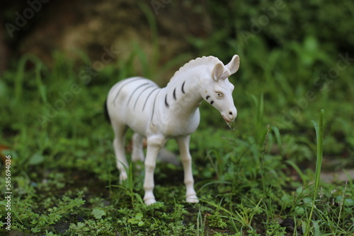 White horse or Zebra animal toy with black dots on grassy ground