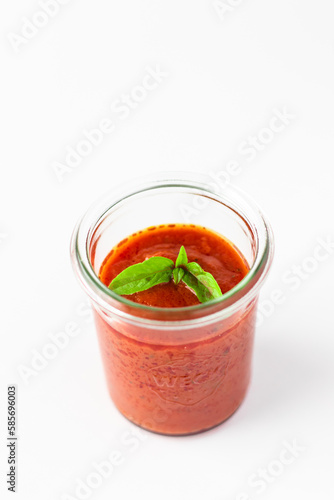 Tomato sauce with basil  in small glass jar on white background.