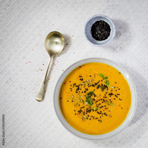 Pumpkin soup with spices and sesame seeds on white background . Flat lay photo.