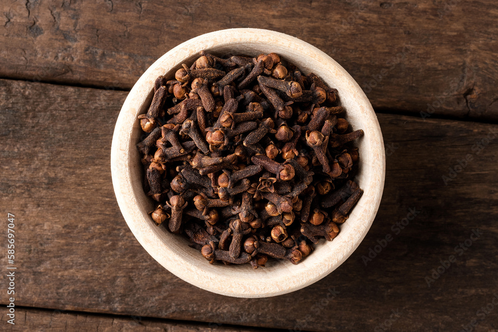 Dried cloves in bowl on wooden table. Close up. Top view Dried cloves in bowl on wooden table. Close up. Top view