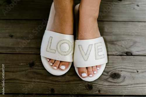 gepflegte Füße einer Braut in Love Hausschuhen vor der Hochzeit photo