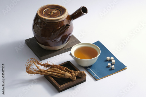 A wooden tray of Angelica root displayed with a bowl of medicine, an earthen pot and few Poria cocos cut into cubes. Medicine for preventing oxidant stress and regulating hormone production photo