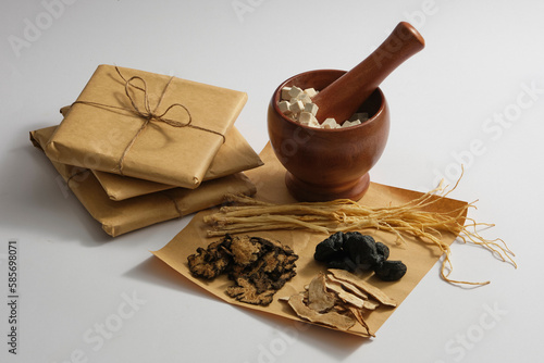 A mortar with Poria cocos and pestle inside, Dang shen, Bai Zhu, Szechuan Lovage Rhizome and Radix rehmanniae displayed around. Herbs may improve brain function and energy levels photo