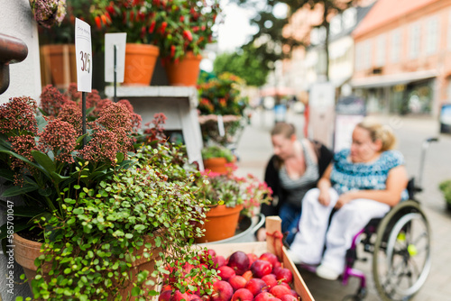 Woman with disability and her assistant choosing flowers in flower shop