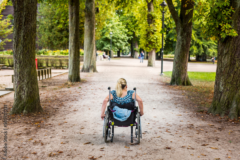 Rear view of disabled woman in wheelchair in park Rear view of disabled woman in wheelchair in park