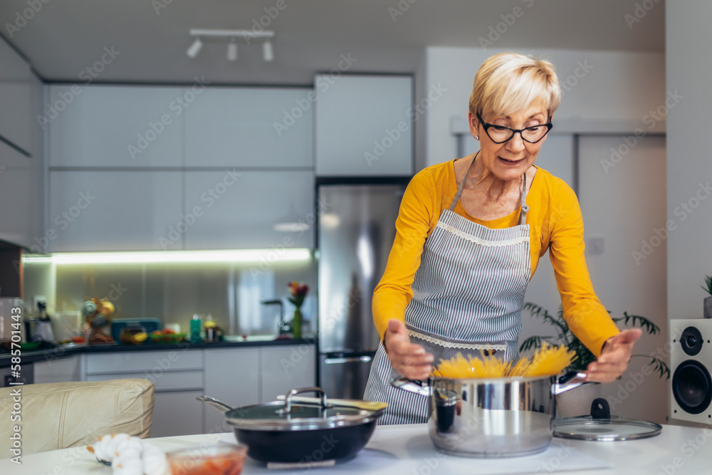 Happy senior woman cooking in her modern kitchen Happy senior woman cooking in her modern kitchen