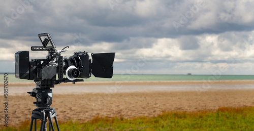 Digital movie camera making film in nature. 
a video camera films on a beach. Wide background with copy space for documentary production. photo