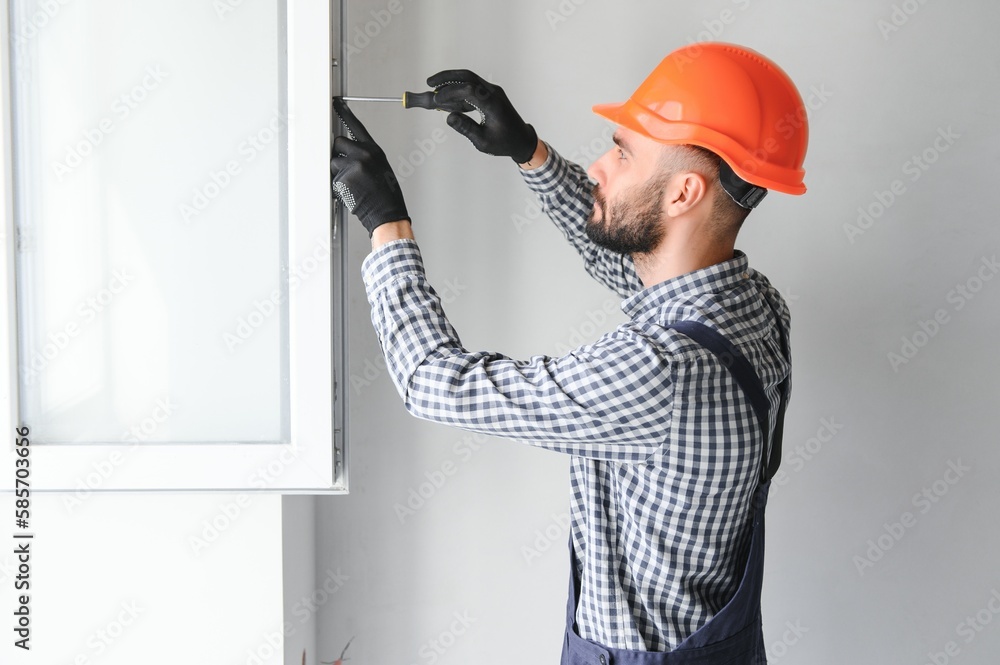 Worker in installing white plastic upvc window on house. Worker in installing white plastic upvc window on house.