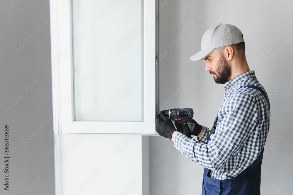 Construction worker installing window in house Construction worker installing window in house
