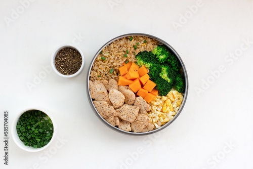 Fried rice with chicken breast has vegetable broccoli pumpkin in bowl on white wood table.
