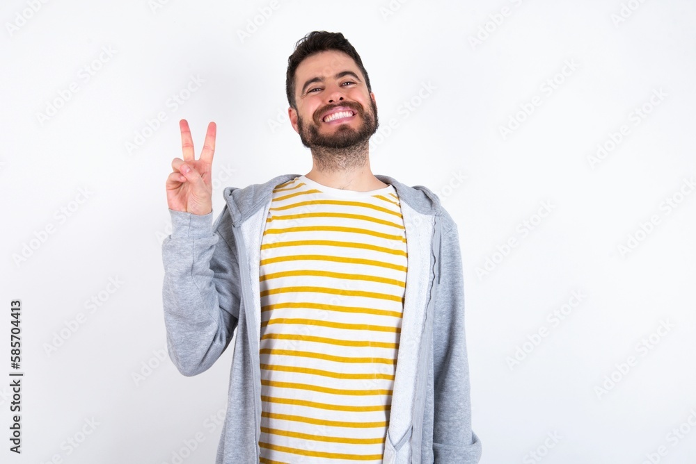 Young caucasian mán wearing trendy clothes over white background smiling with happy face winking at the camera doing victory sign. Number two. Young caucasian mán wearing trendy clothes over white background smiling with happy face winking at the camera doing victory sign. Number two.